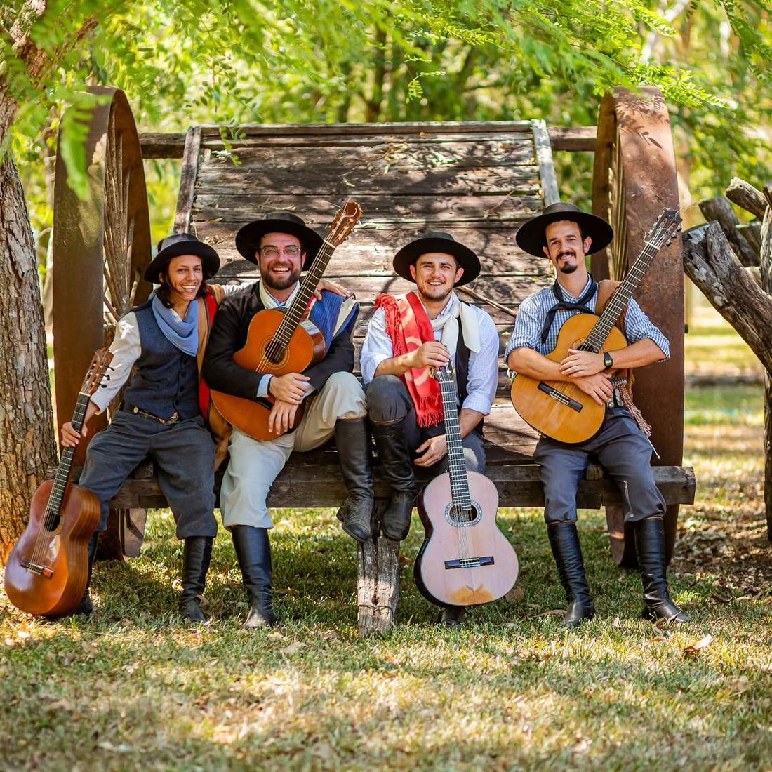 O Quarteto sentado numa carreta antiga, com violões
